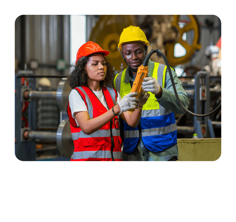 Two individuals in safety vests and hard hats examining an object with focused expressions.